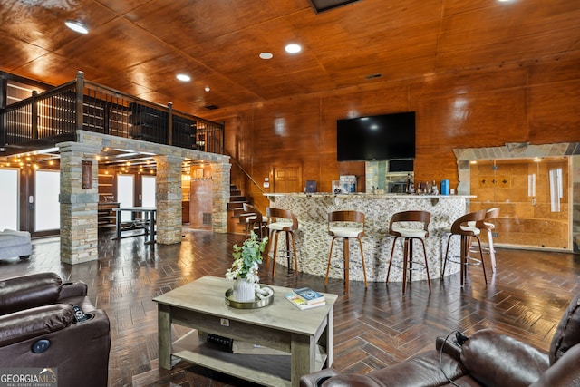 interior space featuring wood walls, parquet flooring, wood ceiling, and decorative columns