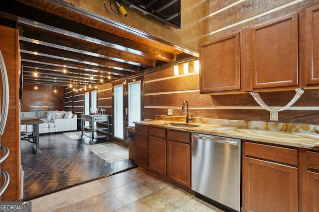 kitchen featuring sink, wooden walls, stainless steel dishwasher, beamed ceiling, and light parquet flooring