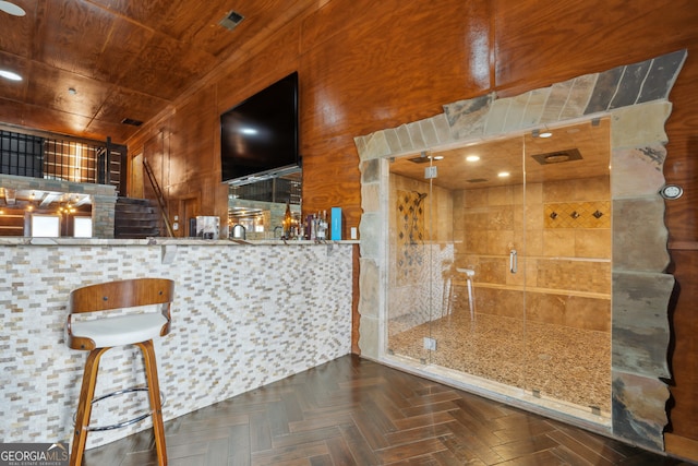 bar with dark parquet flooring, wood ceiling, and wooden walls