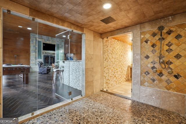 bathroom with a fireplace and tile walls