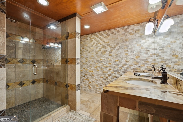 bathroom featuring a shower with door, vanity, tile walls, and tile patterned flooring