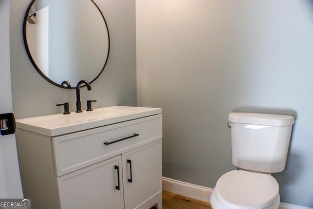 bathroom featuring wood-type flooring, vanity, and toilet