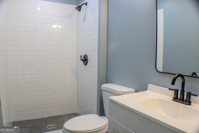 bathroom with tiled shower, vanity, and toilet