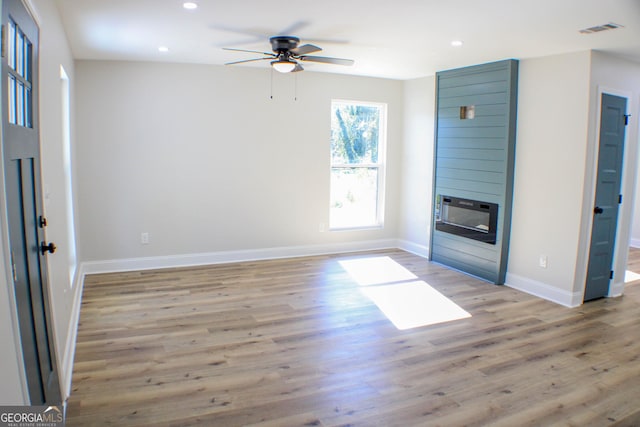 unfurnished living room with a fireplace, light wood-type flooring, and ceiling fan