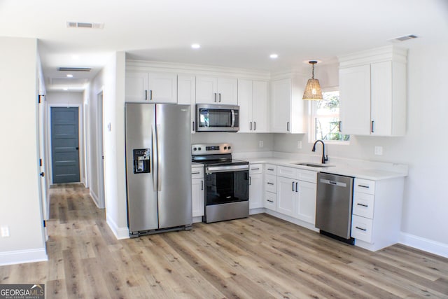 kitchen featuring hanging light fixtures, sink, appliances with stainless steel finishes, light hardwood / wood-style floors, and white cabinetry