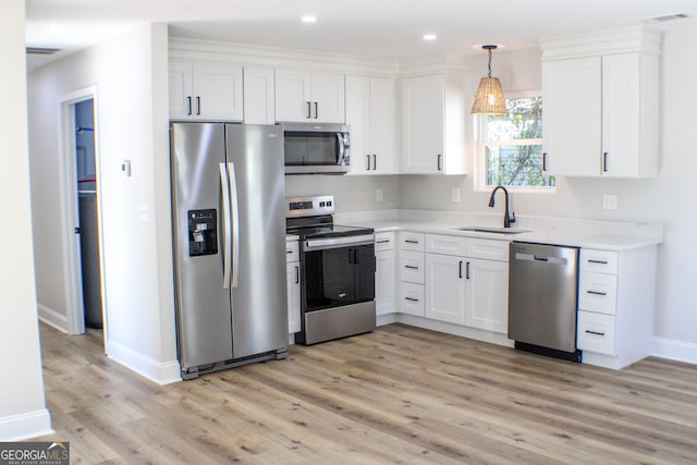 kitchen with stainless steel appliances, sink, light hardwood / wood-style flooring, white cabinets, and hanging light fixtures