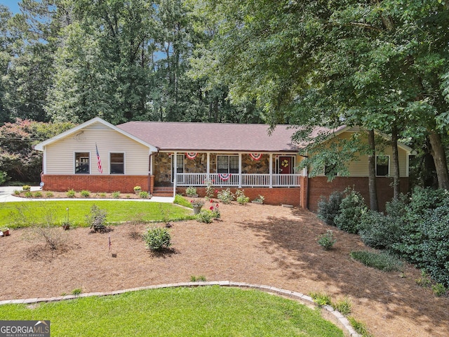 ranch-style home featuring covered porch and a front yard