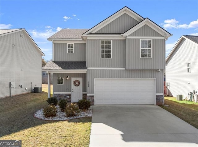 view of front of house featuring a front lawn, central AC unit, and a garage