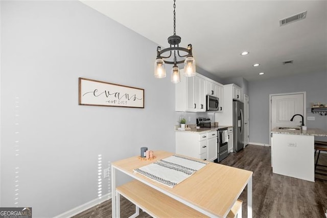 dining space featuring dark hardwood / wood-style flooring, a chandelier, and sink