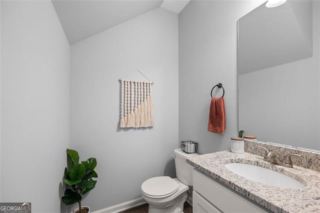 bathroom featuring vanity, toilet, and lofted ceiling