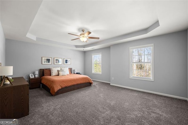 carpeted bedroom featuring a raised ceiling and ceiling fan