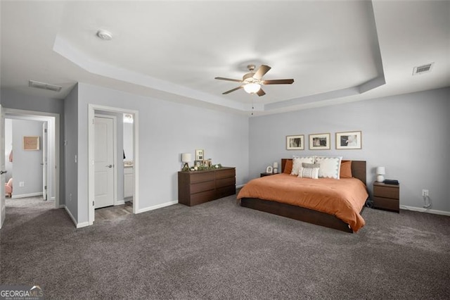 bedroom with ceiling fan, dark carpet, and a raised ceiling