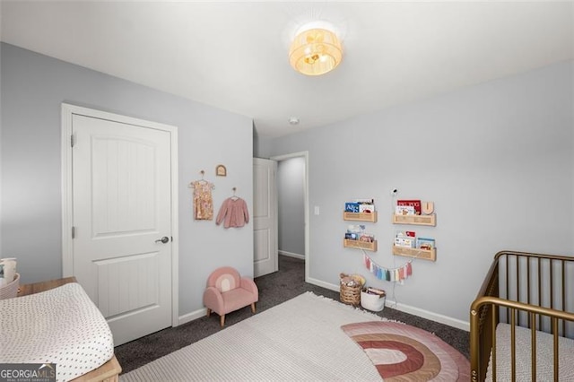 bedroom with a nursery area and dark colored carpet