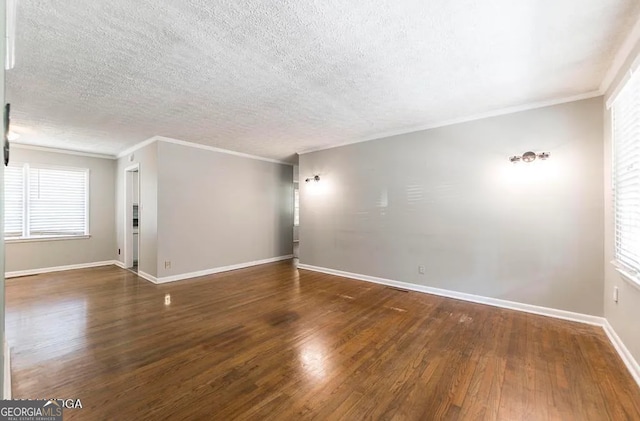 spare room with dark wood-type flooring, a textured ceiling, and ornamental molding