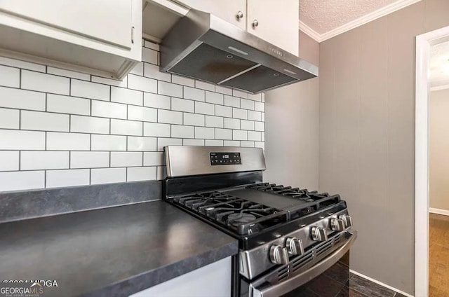 2982 Woodhaven Cir, Macon, GA 31204 - kitchen featuring under cabinet range hood, stainless steel range with gas stovetop, ornamental molding, tasteful backsplash, and white cabinets