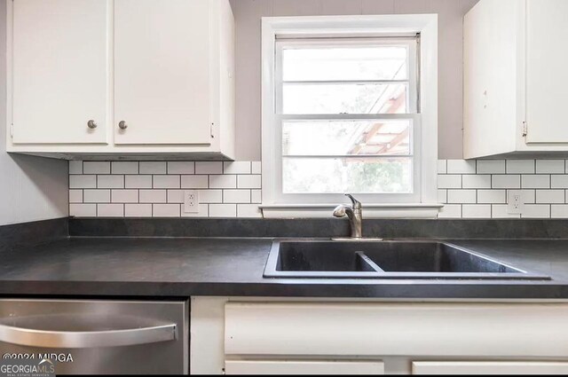 2982 Woodhaven Cir, Macon, GA 31204 - kitchen with dark countertops, white cabinetry, stainless steel dishwasher, a sink, and backsplash