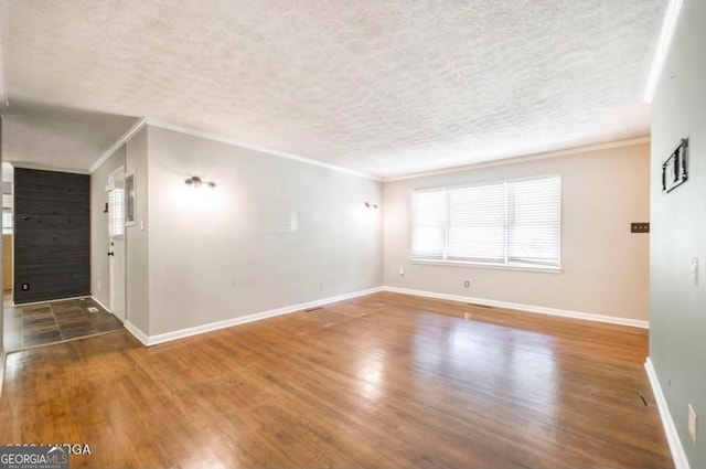 empty room with a textured ceiling, dark hardwood / wood-style flooring, and crown molding