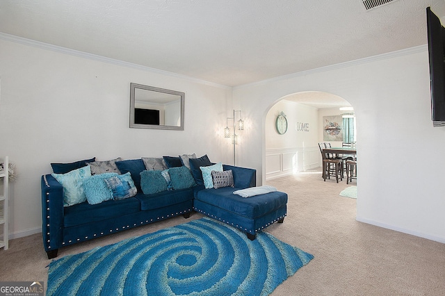 living area featuring arched walkways, a textured ceiling, a wainscoted wall, ornamental molding, and carpet