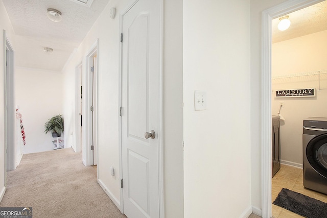 hall featuring washer / dryer, light carpet, and a textured ceiling