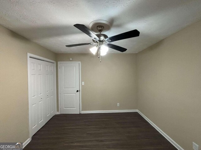 unfurnished bedroom featuring a textured ceiling, dark hardwood / wood-style flooring, a closet, and ceiling fan