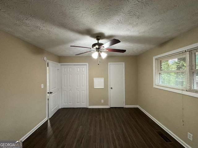 spare room with ceiling fan, dark hardwood / wood-style flooring, and a textured ceiling