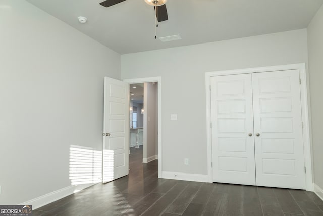 unfurnished bedroom with dark hardwood / wood-style flooring, a closet, and ceiling fan