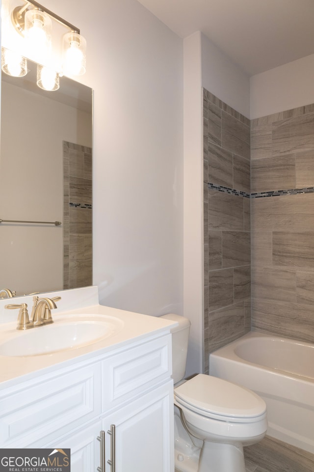 full bathroom featuring vanity, wood-type flooring, tiled shower / bath combo, and toilet