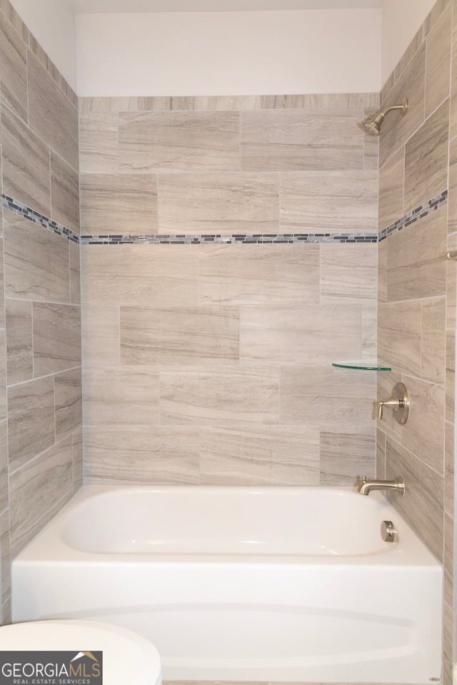 bathroom featuring tiled shower / bath combo and toilet