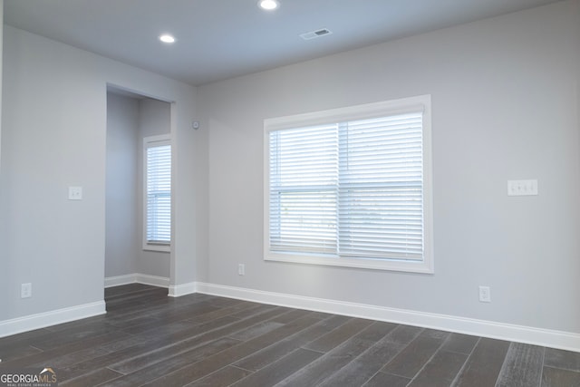 empty room with dark hardwood / wood-style flooring and a wealth of natural light