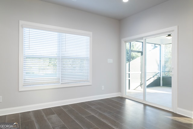 empty room with dark hardwood / wood-style flooring and a healthy amount of sunlight