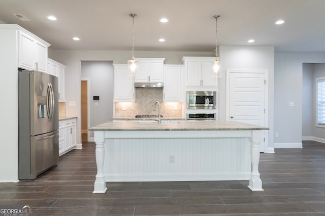 kitchen featuring decorative light fixtures, stainless steel appliances, white cabinetry, and a center island with sink