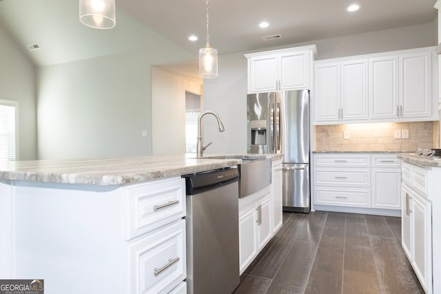 kitchen featuring dark hardwood / wood-style flooring, stainless steel appliances, decorative light fixtures, white cabinetry, and an island with sink