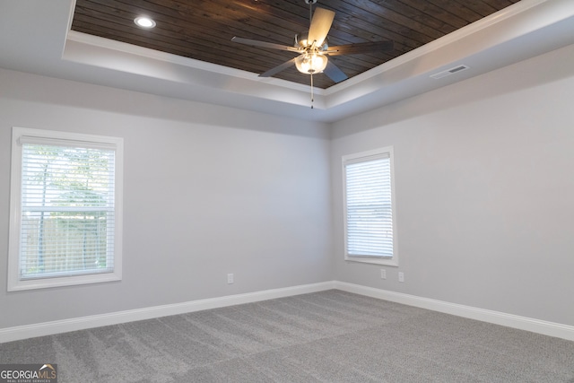 spare room featuring carpet, a raised ceiling, ceiling fan, crown molding, and wooden ceiling