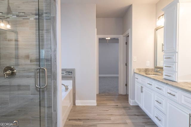 bathroom with plus walk in shower, wood-type flooring, and vanity