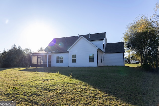 rear view of house featuring a lawn and a sunroom