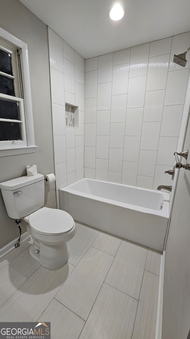 bathroom featuring tiled shower / bath combo and toilet