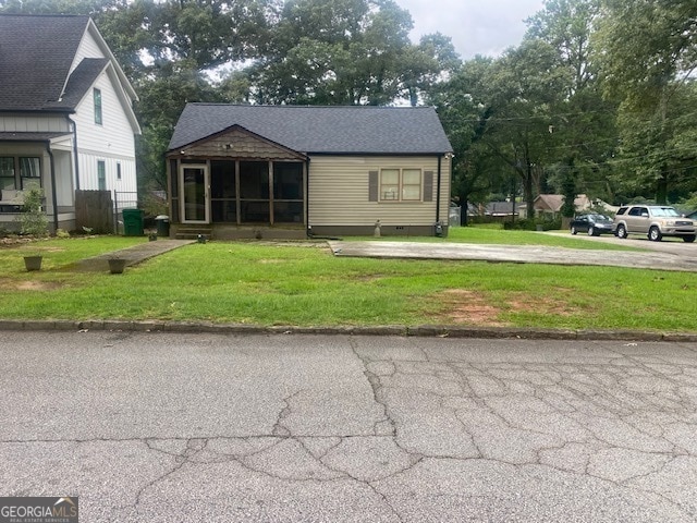 view of front facade with a front lawn and a sunroom