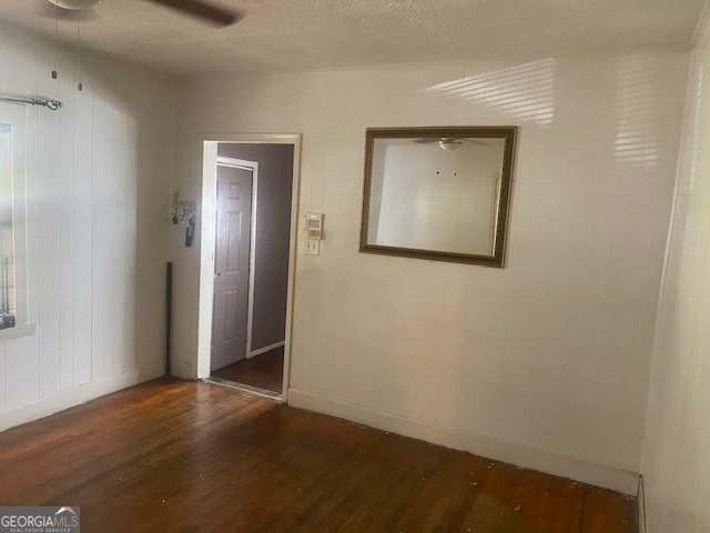 unfurnished room featuring a textured ceiling, dark hardwood / wood-style flooring, and ceiling fan