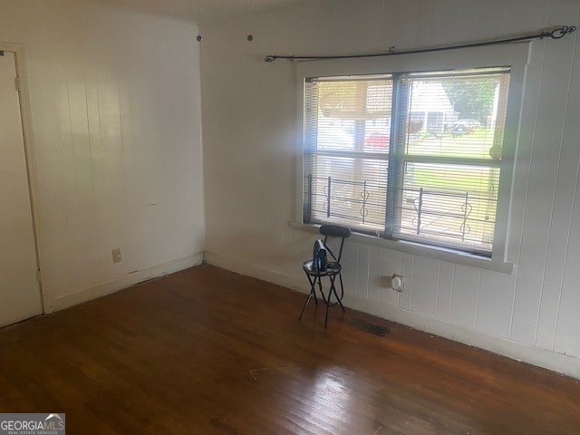 spare room featuring dark hardwood / wood-style flooring and wooden walls