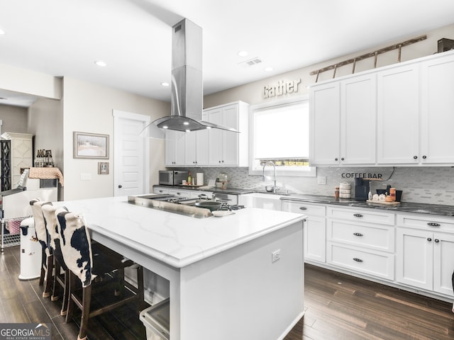 kitchen featuring a center island, dark wood-type flooring, light stone counters, island range hood, and white cabinets