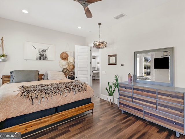 bedroom with dark hardwood / wood-style floors and ceiling fan with notable chandelier