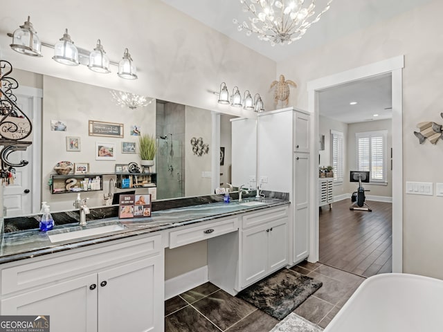 bathroom featuring vanity, wood-type flooring, plus walk in shower, and an inviting chandelier