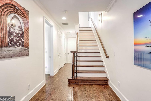 stairs with hardwood / wood-style flooring and crown molding