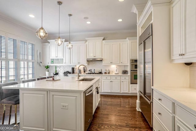 kitchen featuring a center island with sink, decorative light fixtures, light stone counters, and sink