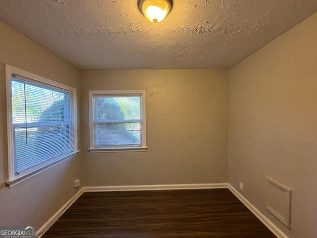 empty room featuring a textured ceiling and dark hardwood / wood-style flooring