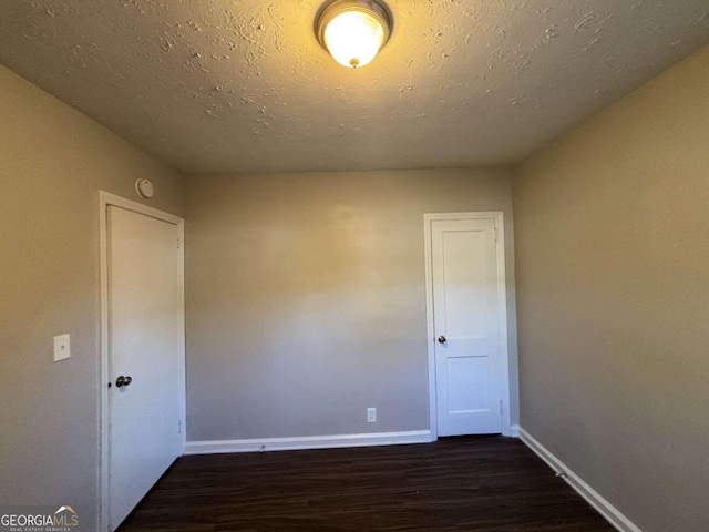 unfurnished bedroom with a textured ceiling, a closet, dark hardwood / wood-style floors, and ceiling fan