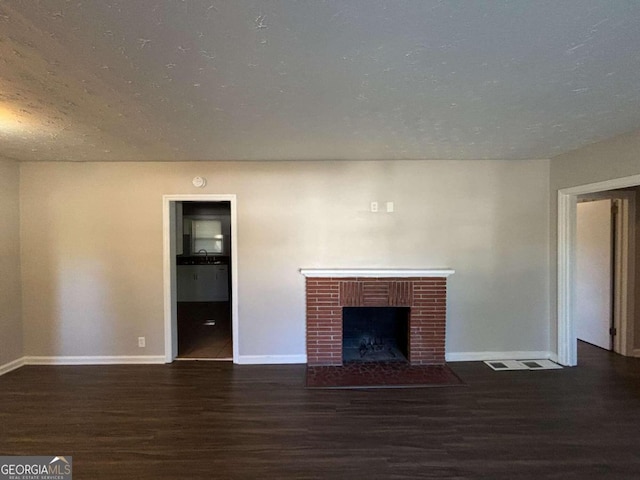 unfurnished living room featuring a textured ceiling, dark hardwood / wood-style floors, and a brick fireplace