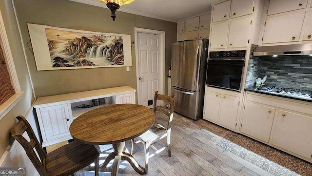 kitchen featuring decorative backsplash, white cabinets, light hardwood / wood-style floors, black oven, and stainless steel refrigerator