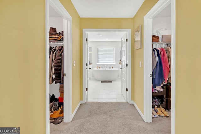 corridor featuring baseboards, carpet floors, and tile patterned flooring