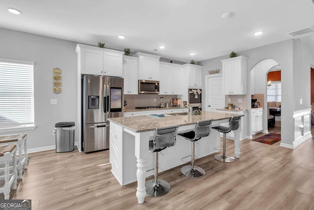 kitchen featuring arched walkways, white cabinetry, visible vents, and appliances with stainless steel finishes
